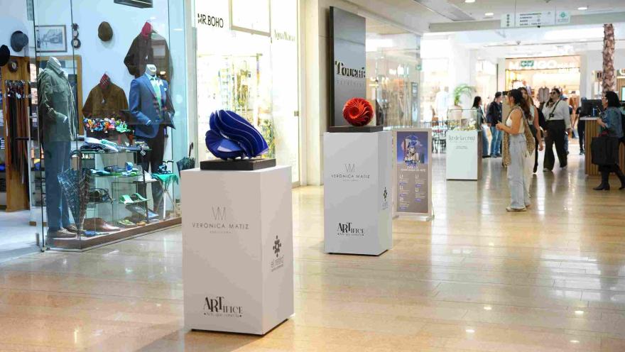 Un elegante pasillo del Centro Comercial El Retiro exhibe piezas de diseño y arte contemporáneo, creando un ambiente sofisticado entre boutiques, vitrinas y visitantes.