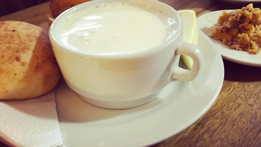 Taza de bebida caliente acompañada de pan y dulces tradicionales.