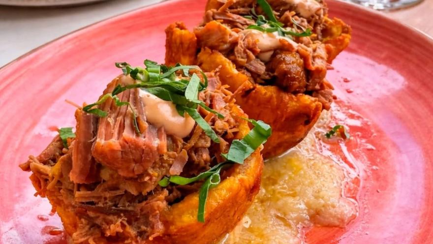 A dish of pulled pork served on a crispy base with sauce.