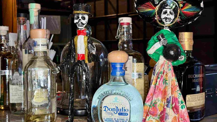 Bottles of tequila and liquor accompanied by decorative Mexican figurines.