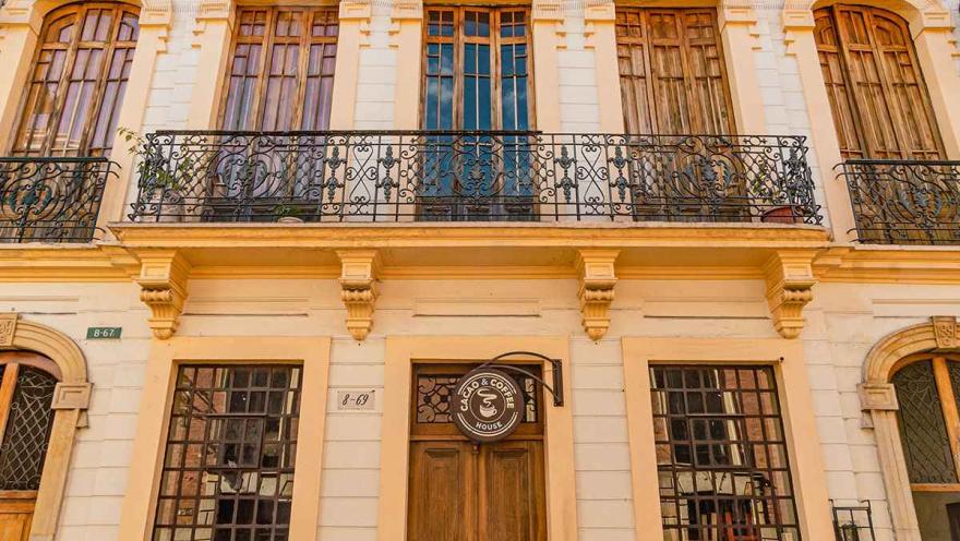 Fachada colonial de La Candelaria, con balcones de hierro forjado, puertas y ventanas de madera y un café tradicional.