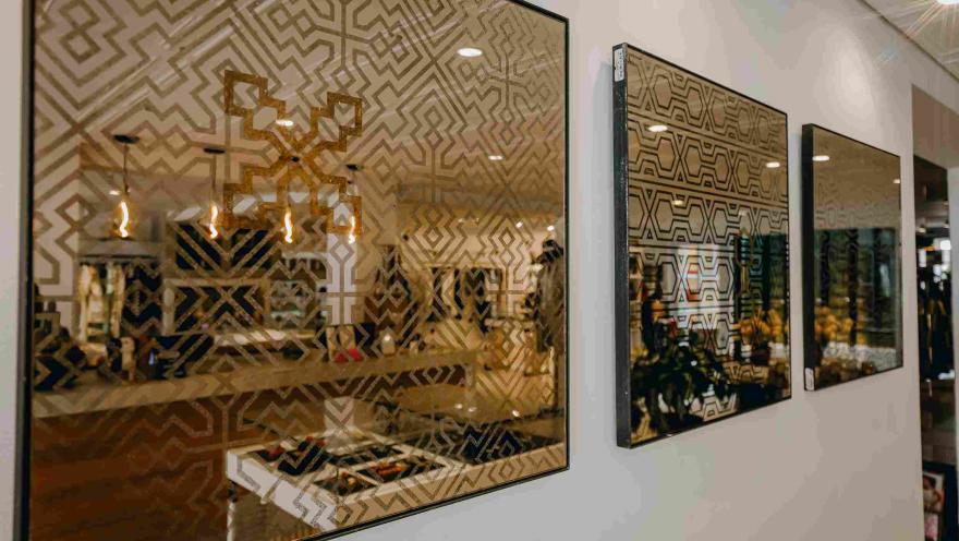 Obras decorativas con patrones geométricos inspirados en motivos indígenas, exhibidas en las paredes de un espacio de diseño y artesanías.