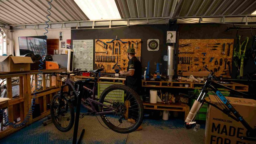  Taller especializado en bicicletas, donde se observan varias bicicletas de montaña, herramientas y equipos organizados para labores de mantenimiento y reparación. El espacio refleja el ambiente técnico y especializado de este tipo de establecimientos.