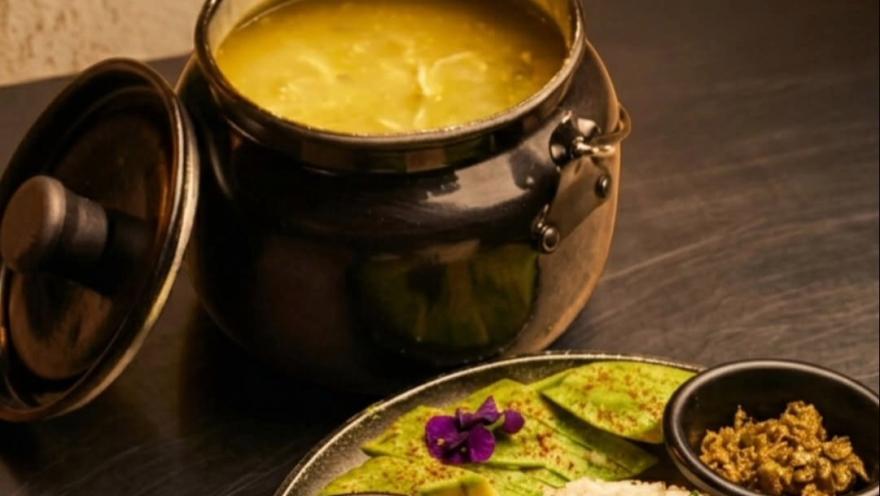 Ajiaco santafereño servido en una olla tradicional, acompañado de arroz, aguacate y otros complementos típicos de la cocina bogotana.