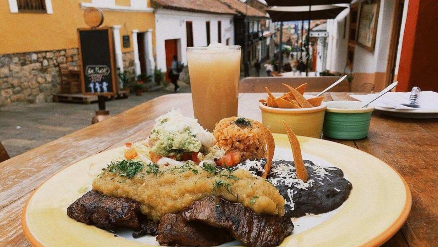 A Mexican dish featuring medallions of beef, breaded chicken, rice, beans, guacamole, and salad, served on a terrace in La Candelaria.
