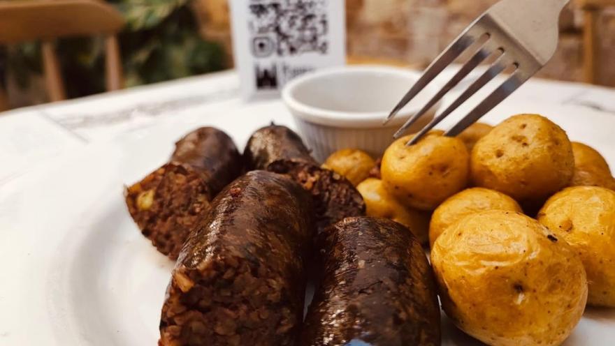 Morcillas colombianas acompañadas de papas criollas, servidas en un plato.