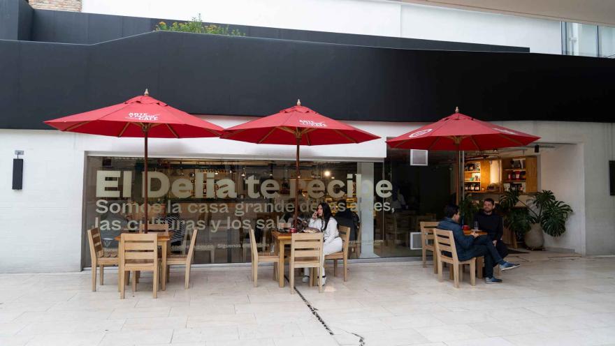 Terraza exterior con sombrillas rojas de Arte y Pasión Café, mesas de madera y clientes compartiendo afuera. 