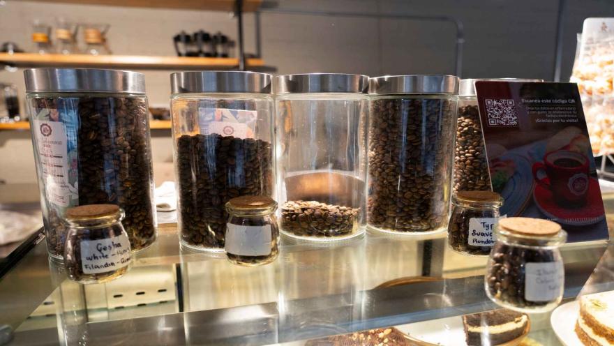 Frascos de vidrio con granos de café especial en exhibición junto a un código QR para factura electrónica. 