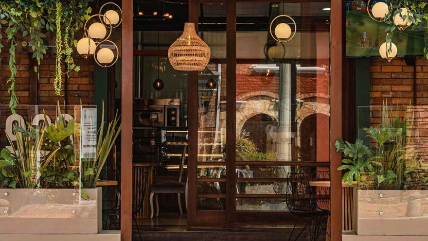 Restaurante de la Zona G con fachada de ladrillo, grandes ventanales, vegetación y una cálida iluminación interior.