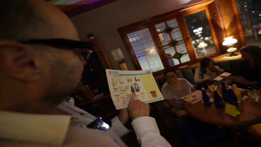 Persona señalando un folleto explicativo durante un taller de ginebra en Gin Garden con asistentes de fondo. 