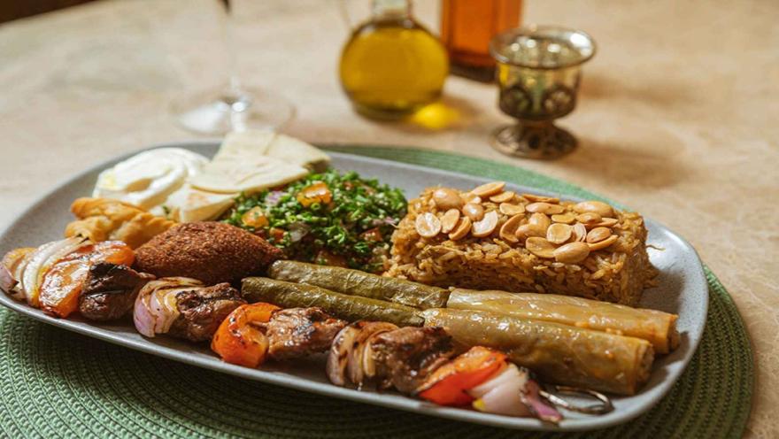 lato de cocina árabe con brochetas de carne y vegetales, arroz con almendras, falafel, tabulé y pan de pita.