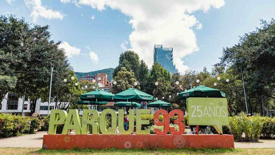 Parque de la 93, con su emblemático letrero, zonas verdes, sombrillas de restaurantes y edificios entre los árboles.