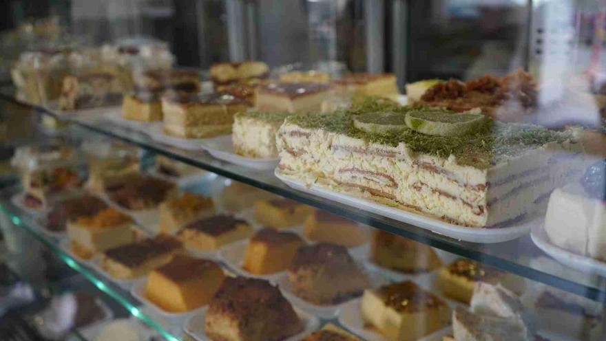 Vitrina de vidrio exhibiendo múltiples porciones de postres, bizcochos y tartas heladas en bandejas. 