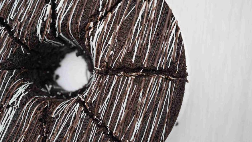 Plano cenital en detalle de una rosca de chocolate decorada con hilos de cobertura blanca y oscura.