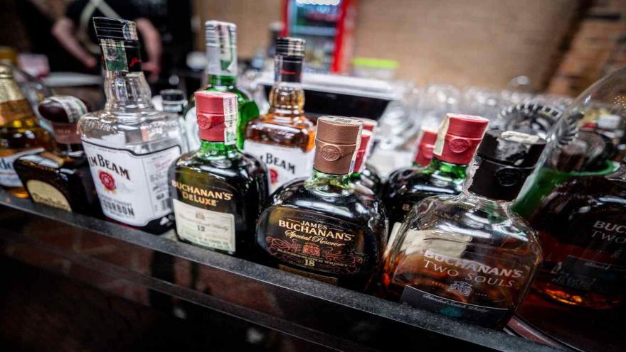  Colección de botellas de whisky y licores premium exhibidas en fila sobre una barra de bar.