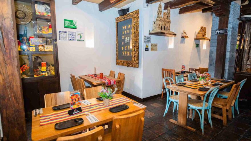 Zona de comedor con vitrina artesanal, réplica de iglesia colonial en repisa y sillas de madera y tono celeste.