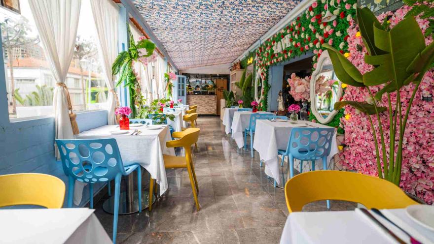 Pasillo del restaurante visto desde un extremo, mostrando el suelo brillante, mesas vestidas y sillas coloridas.