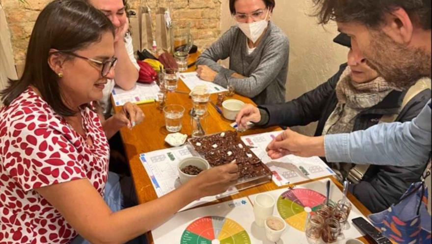 Grupo de participantes en una mesa decorando una bandeja de chocolate en un taller de cata de cacao. 