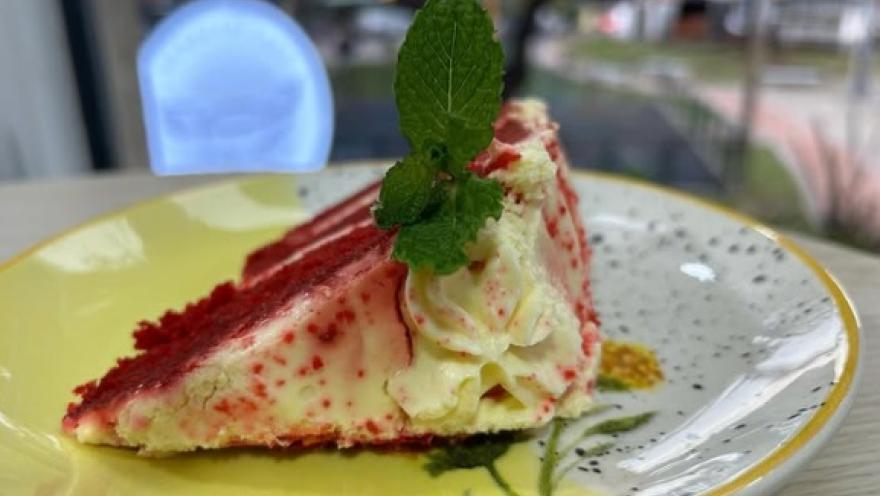 Porción de torta de frutos rojos con crema y hierbabuena.