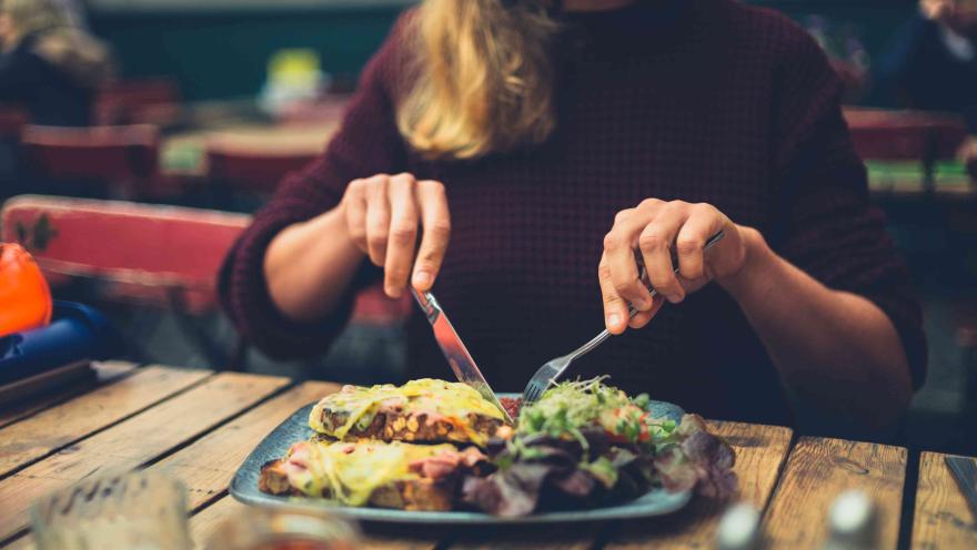 Comensal disfrutando de un plato en un restaurante, acompañado de ensalada y otros alimentos.