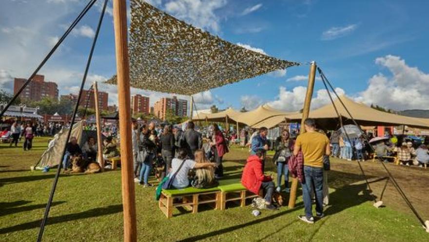 Público disfruta de la oferta gastronómica y cultural de un festival al aire libre en un parque.