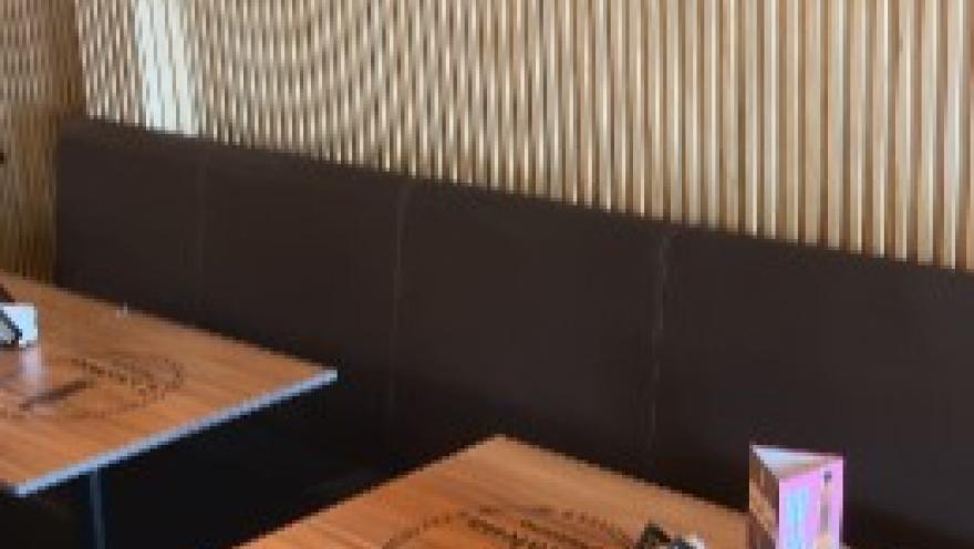 Ambiente de L’altalena Pizzería, con mesas de madera y decoración cálida.