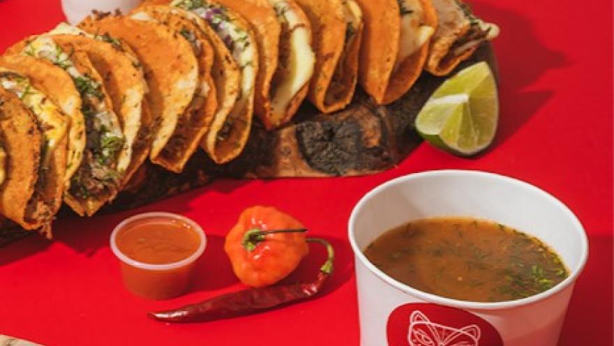 Tacos de birria acompañados de consomé, limón y salsas de la casa.