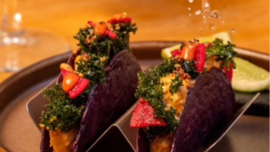 Tacos de tortilla morada rellenos y acompañados de vegetales frescos, servidos en un plato de presentación.