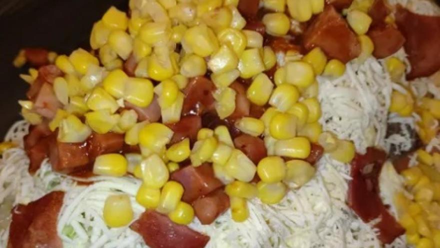 Salchipapa con salchicha, maíz dulce, queso rallado y salsas.