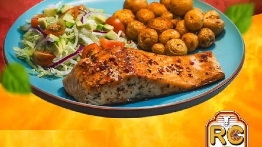 Filete de salmón acompañado de ensalada fresca y papas doradas.