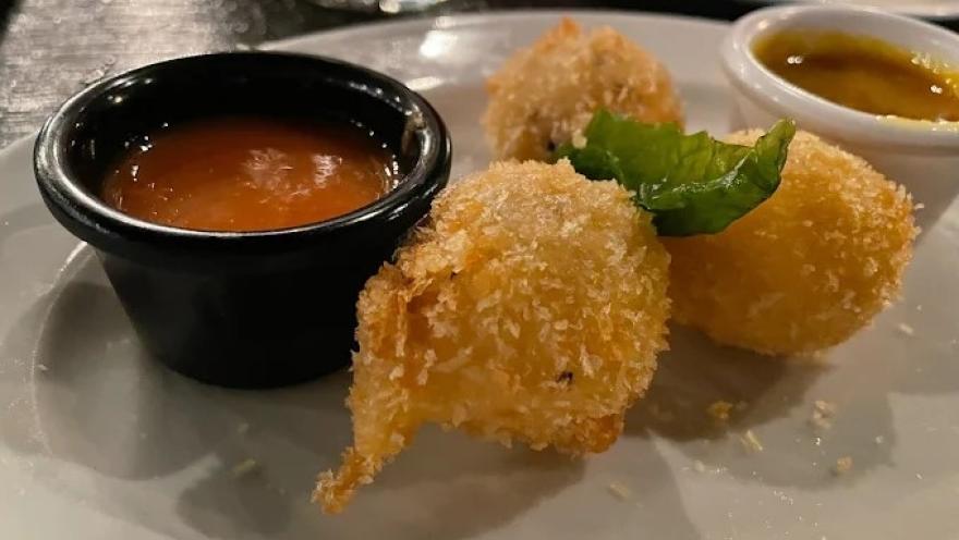 Croquetas doradas y crujientes acompañadas de salsas para degustar, decoradas con hojas de hierbabuena.