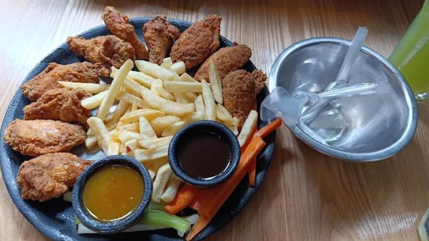 Selección de pollo apanado y papas fritas, acompañada de salsas y vegetales frescos.
