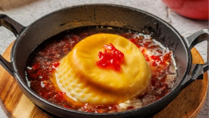 Preparación de pasta rellena servida en sartén, acompañada de salsa de tomate y queso fundido.