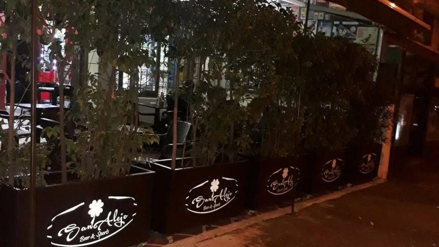 Terraza exterior de Sanalejo Beer & Sports, rodeada de vegetación y con ambiente nocturno.