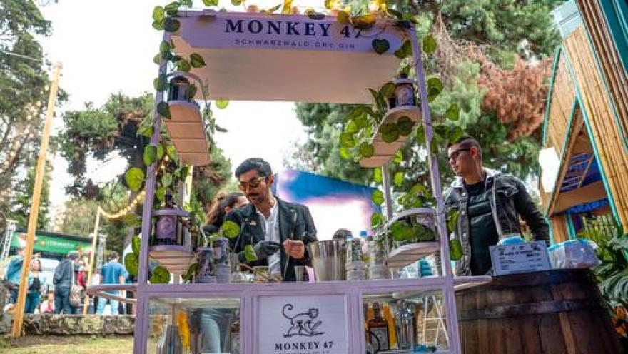  Puesto de bebidas Monkey 47 en un festival gastronómico, rodeado de visitantes.