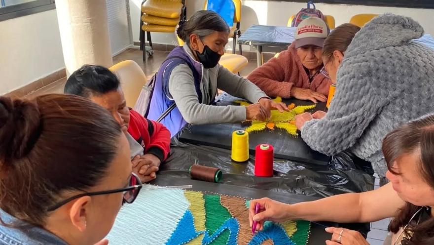 Personas adultas participan en un taller comunitario de tejido y elaboración de artesanías.