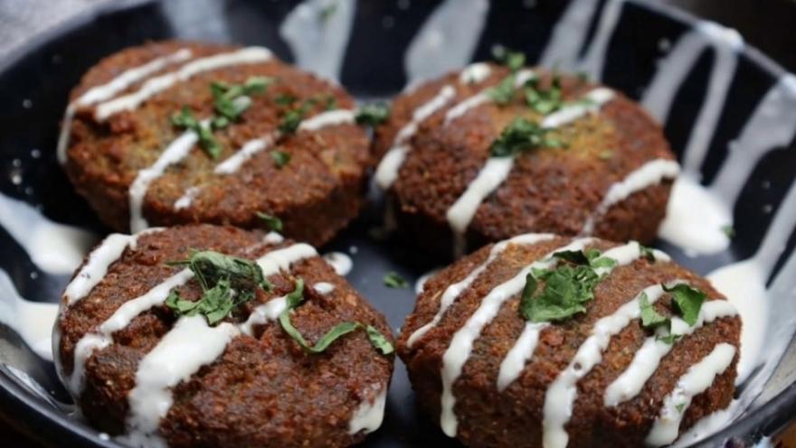 Croquetas de kibbeh servidas con salsa de yogur y hierbas frescas.