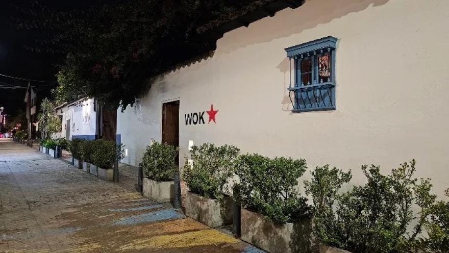 Fachada de WOK, con arquitectura colonial, jardines y el distintivo logo del restaurante.