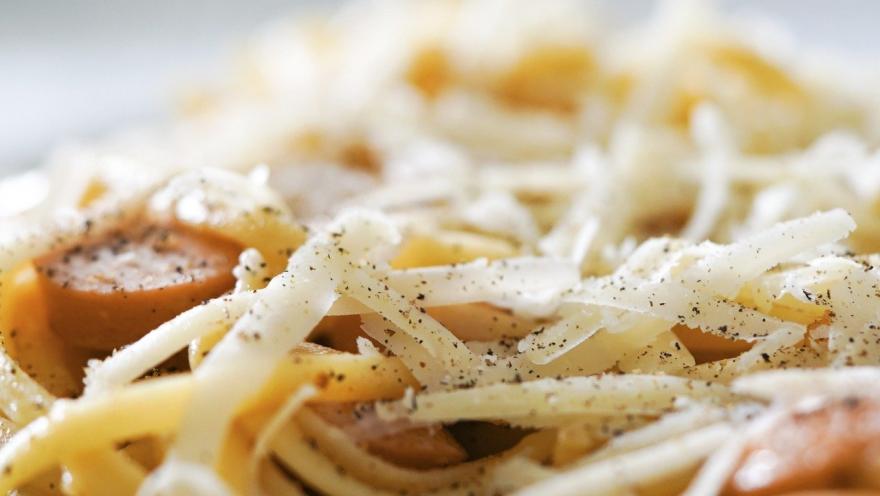 Pasta italiana con queso rallado y pimienta negra, presentada en un plato blanco.