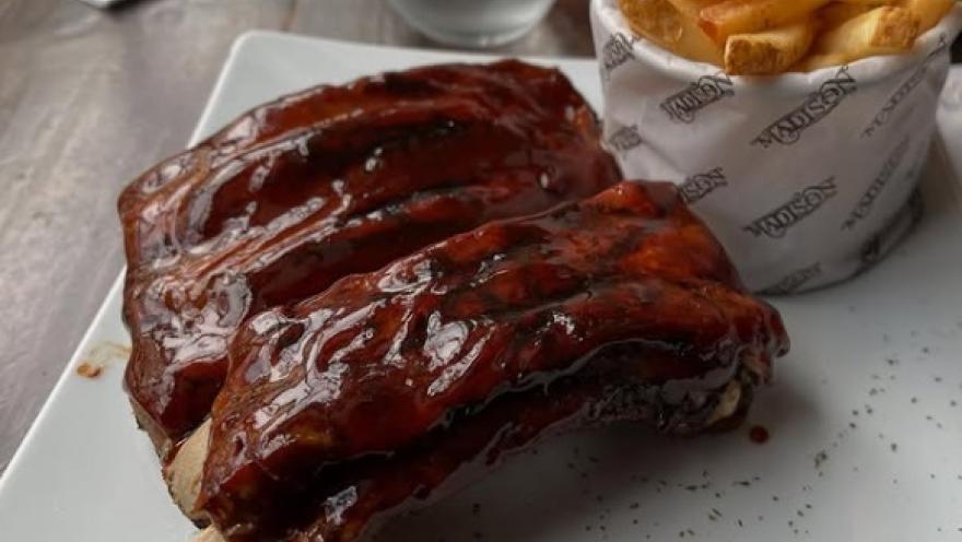 Costillas de cerdo bañadas en salsa BBQ, acompañadas de papas fritas.