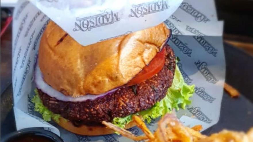 Hamburguesa artesanal con carne, lechuga, tomate y cebolla, acompañada de aros de cebolla y salsa.