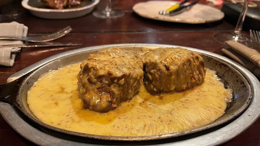 Medallones de cordero bañados en una cremosa salsa, servidos en un plato de presentación.