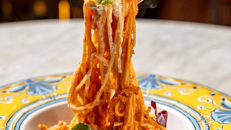 Pasta larga con salsa de tomate y queso, servida en un plato de inspiración italiana. 