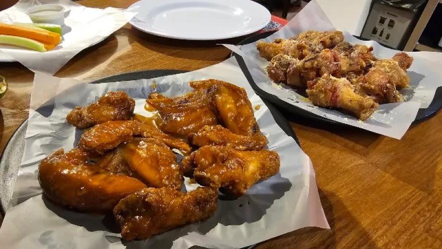 Alitas de pollo con diferentes salsas, servidas en bandejas para compartir.