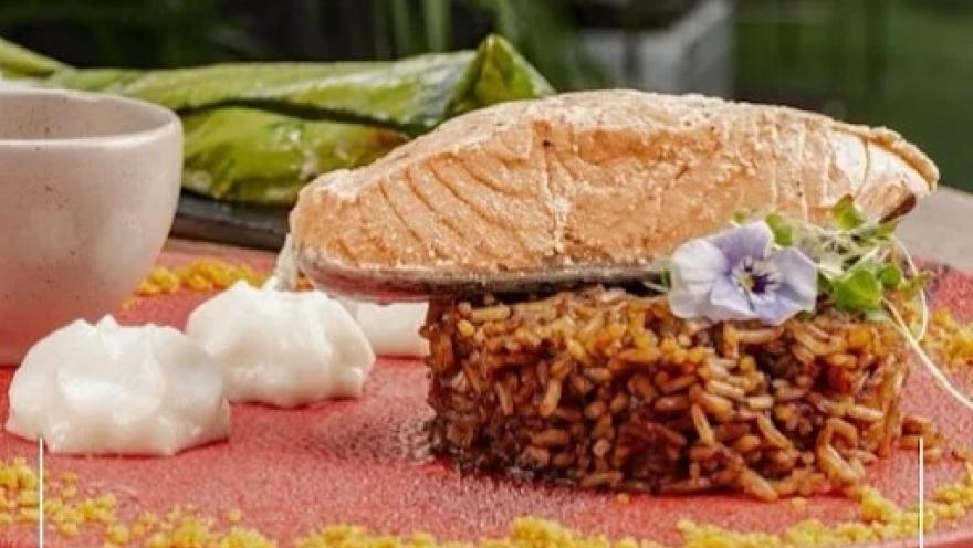 Plato de arroz acompañado de un filete de pescado, vegetales y salsas, presentado de forma creativa.