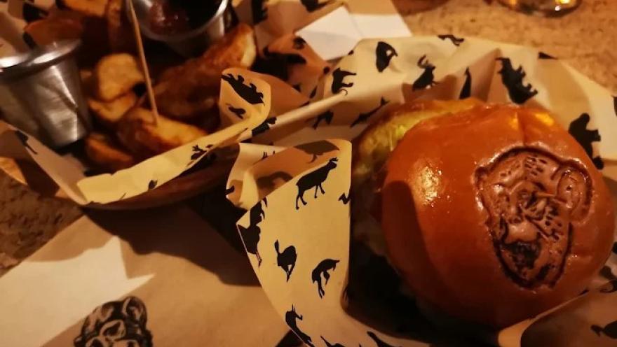 Hamburguesa acompañada de papas fritas, servida en una presentación con el característico diseño de El Mono Bandido.