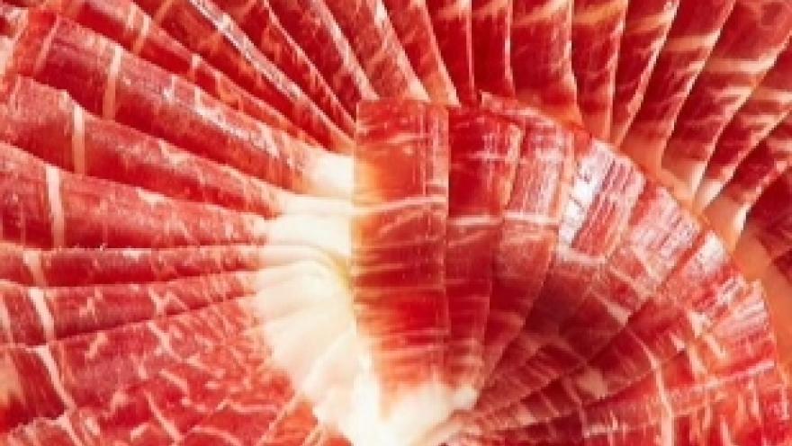Láminas finas de jamón curado italiano dispuestas en forma circular sobre un plato.
